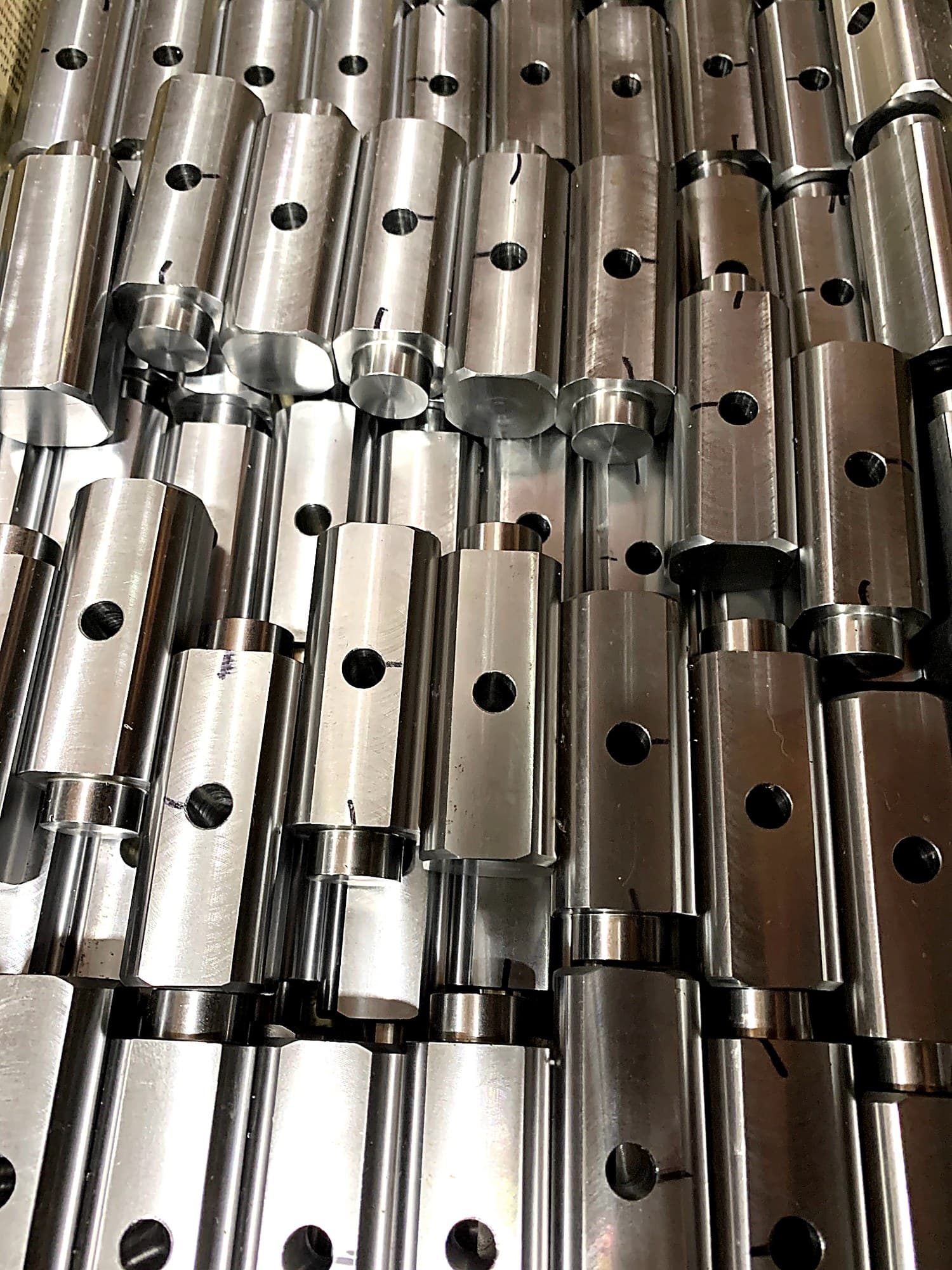 Stacked machined shafts with drilled holes.