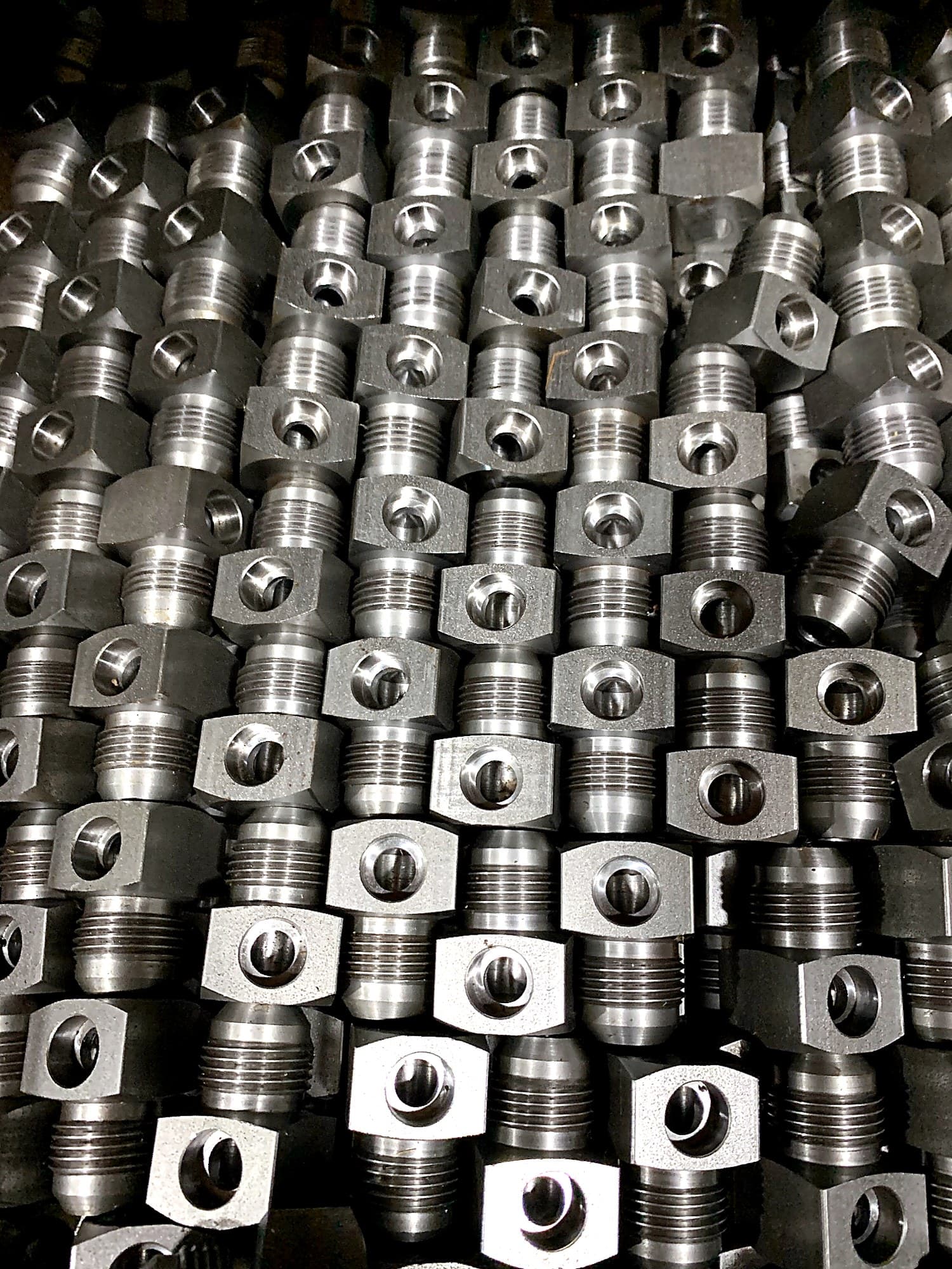 Bin of precision machined threaded fittings.