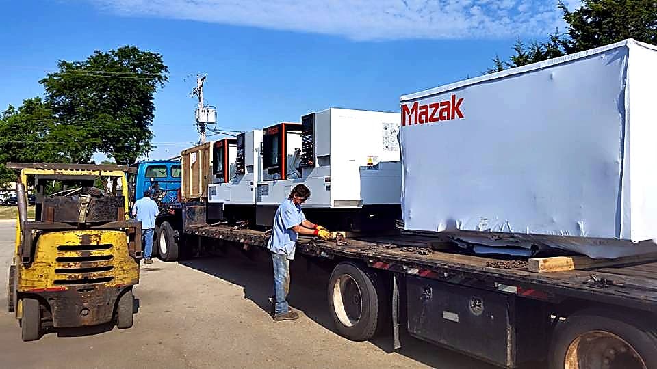 Mazak machines on a flatbed during delivery and unloading.